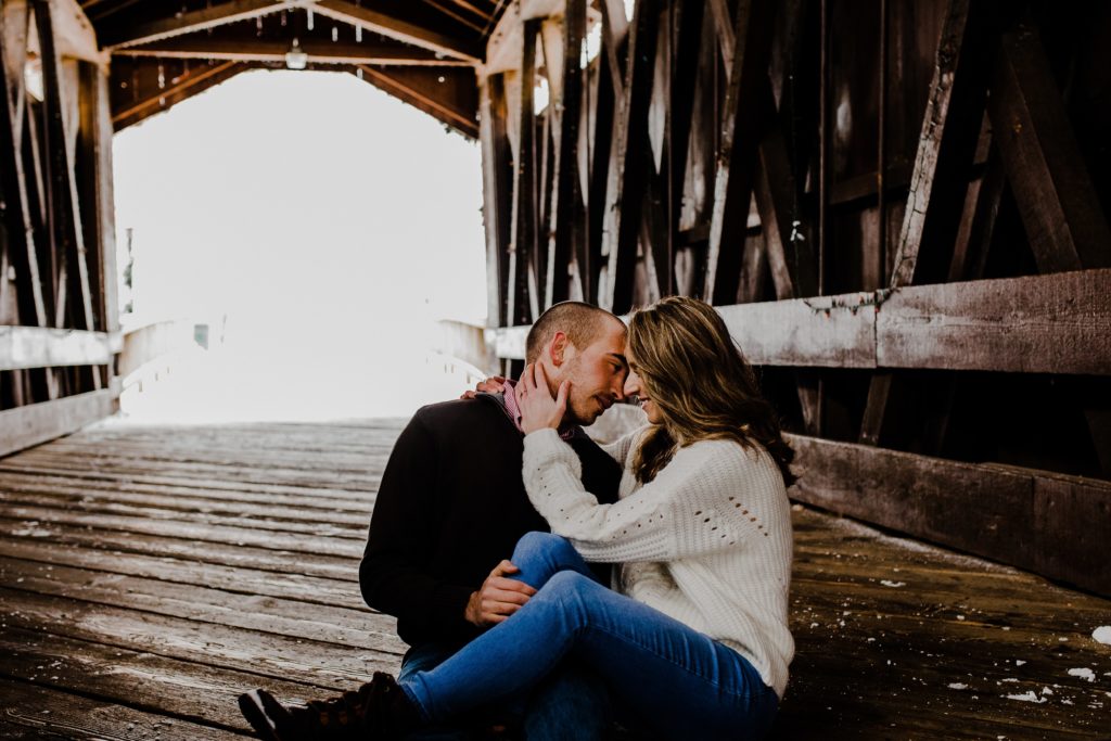 Couple sitting under covered bridge face to face